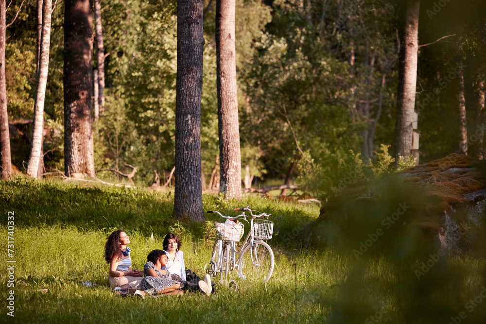 Young female friends relaxing in meadow in summer Young female friends relaxing in meadow in summer