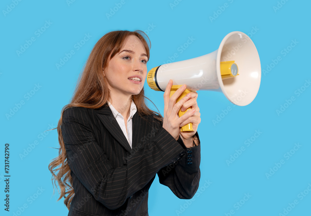 Woman in smart jacket making an announcement with a megaphone on blue background. People have sincere emotions, lifestyle concepts. Mock-up copy space. Screaming in megaphone Woman in smart jacket making an announcement with a megaphone on blue background. People have sincere emotions, lifestyle concepts. Mock-up copy space. Screaming in megaphone