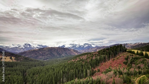 the view over a valley on a cloudy day with snow capped mountains