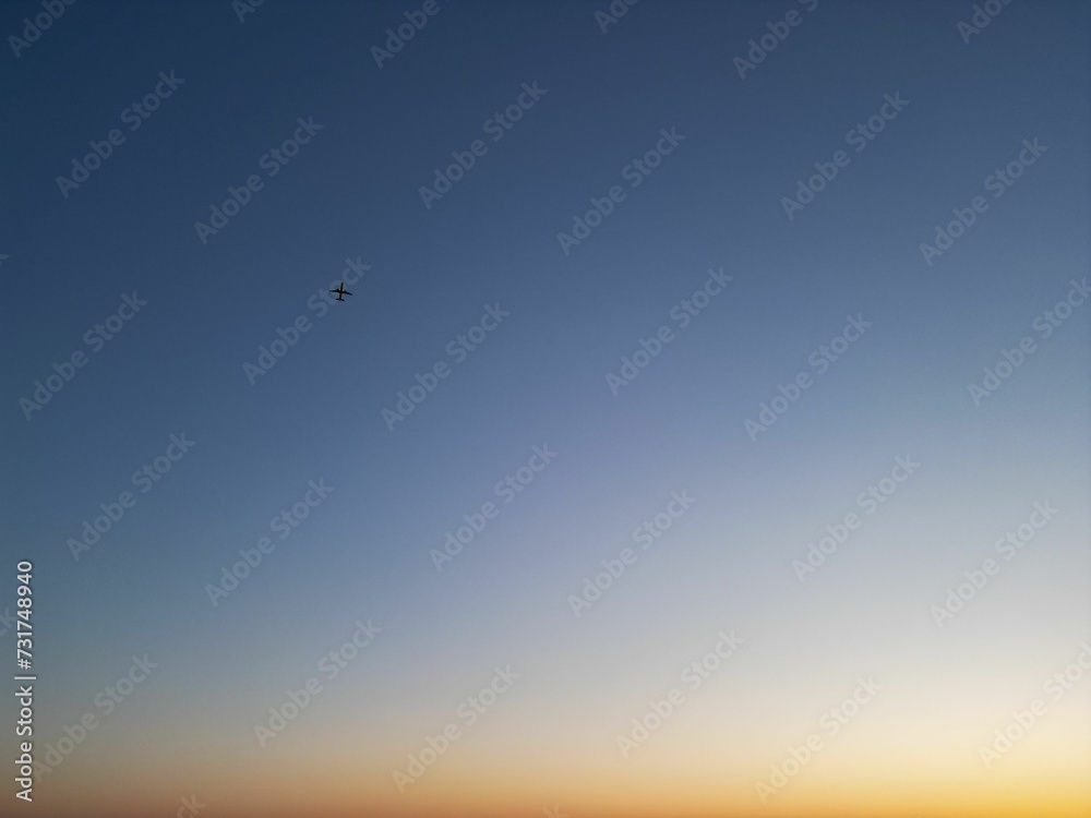 Airplane flying in the blue sky at sunset