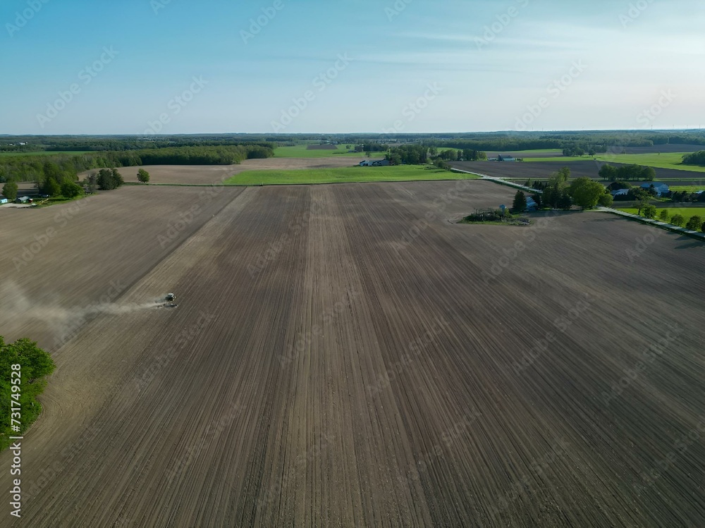 Aerial view of a vast farm field with multiple tractors in action