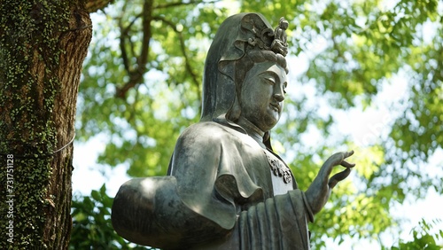 Aged Hindu goddess Devi statue stands on a lush green backdrop of trees