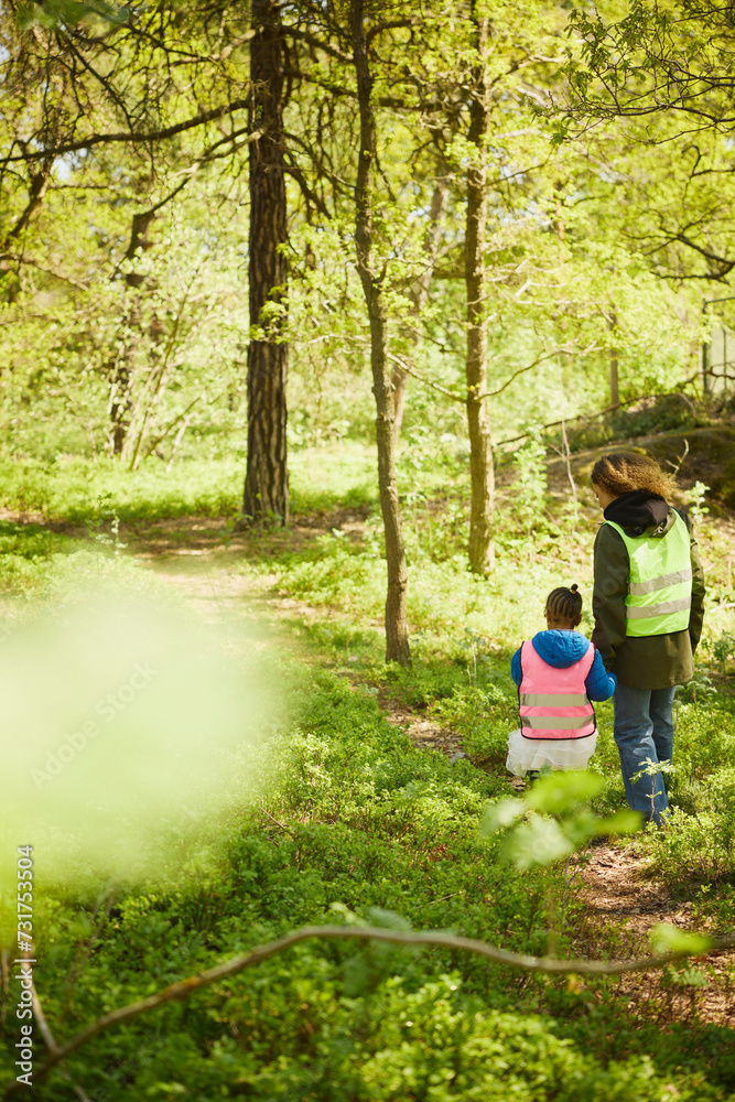 Rear view of woman and girl walking amidst plants in forest Rear view of woman and girl walking amidst plants in forest