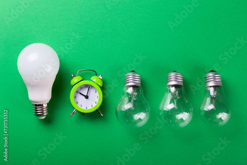 Flatlay Clock with light bulb, calculator on a green background. Minimalism. Top view. Concept ecology, save planet earth, idea, save energy, economy, saving. Earth day..