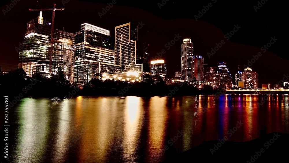 Stunning nighttime cityscape featuring illuminated skyscrapers on either side of the river