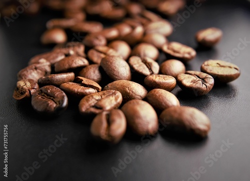 Pile of freshly roasted coffee beans scattered on a black table