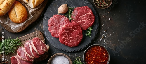 Raw beef schnitzel displayed on a dark background, viewed from above, alongside other butcher products.
