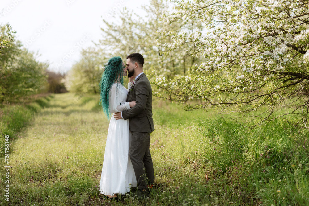 a bearded groom and a girl with green hair are walking