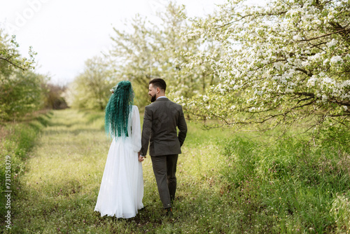 a bearded groom and a girl with green hair are walking © omelnickiy