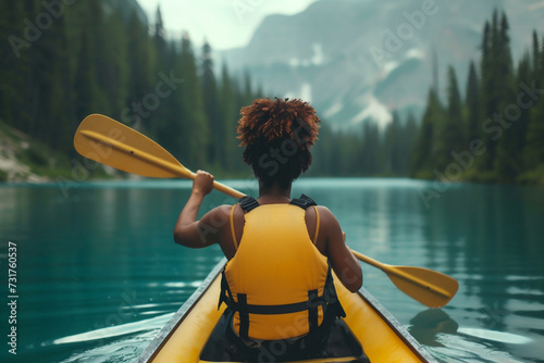 Rear view of kayaker woman paddles her kayak on a mountain lake at sunset © elinorka