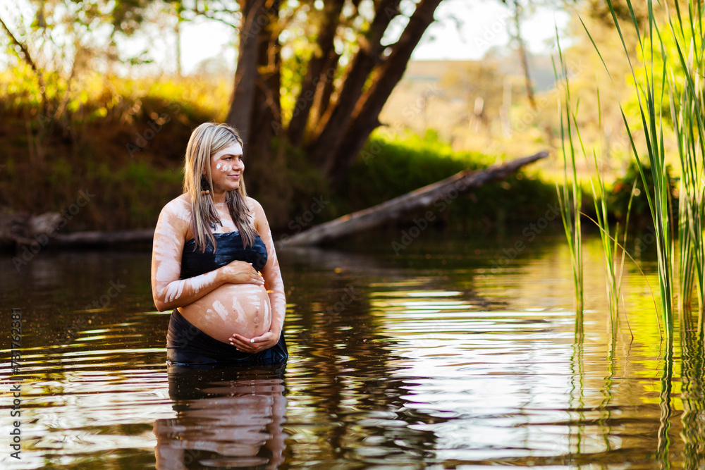 Pregnant Aboriginal Australian woman in traditional ochre body paint in rippling water Pregnant Aboriginal Australian woman in traditional ochre body paint in rippling water