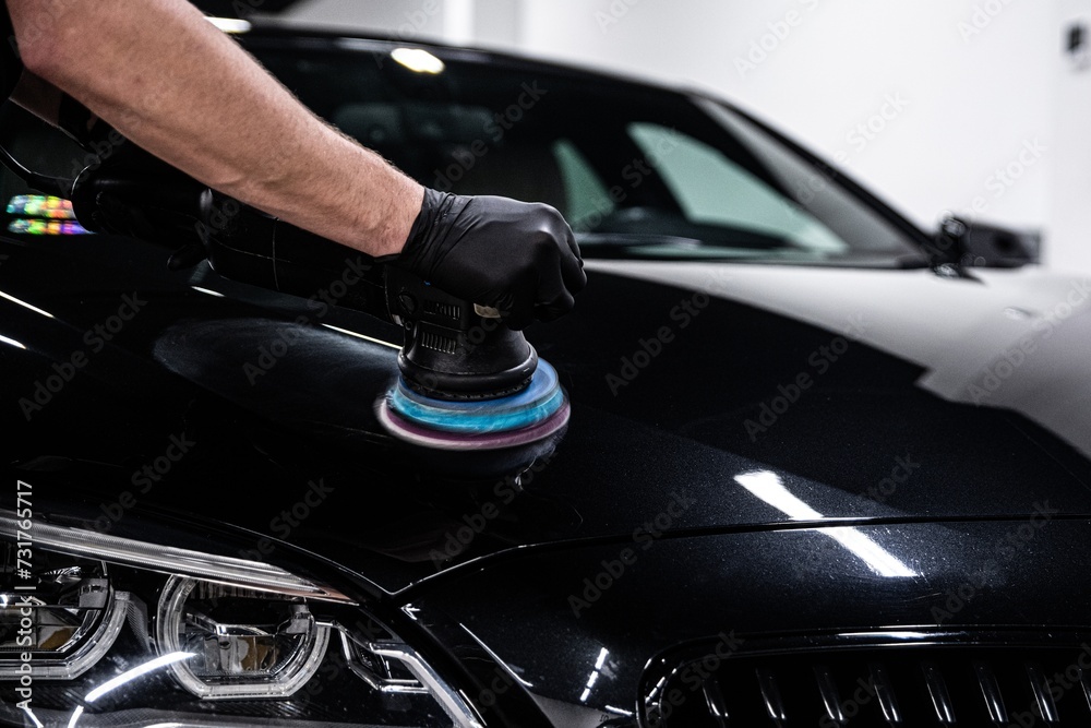 Car detailing worker polishing black car body with electric polisher Car detailing worker polishing black car body with electric polisher