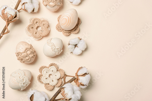 Craft eggs, knitted and cotton flowers on soft beige background. Top view. Copy space