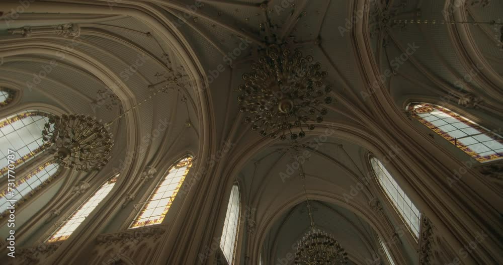 High ceiling of gothic church. High rise windows with sun rays and gothic style. Medieval style. Cathedral with vintage style. Catholic cathedral with high windows and dangling chandelier. Warm colors