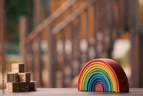 Brightly coloured wooden rainbow learning puzzle in nature-based playground environment photo