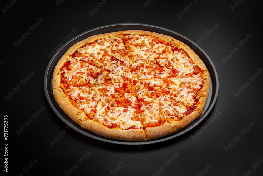 Pizza Margherita with tomatoes and cheese. On a black background.