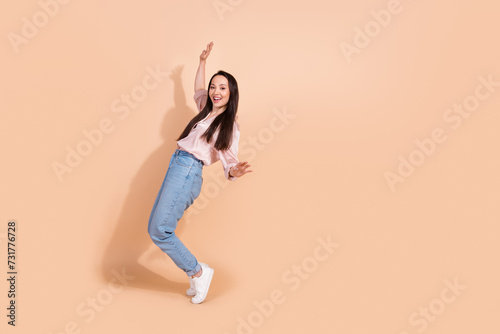 Full length photo of satisfied girl wear pink shirt jeans pants stand on tiptoes near sale empty space isolated on pastel color background