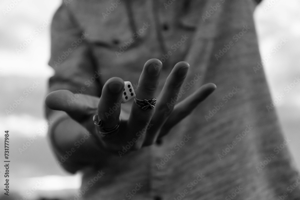 Grayscale shot of a hand playing with dice in a game of chance