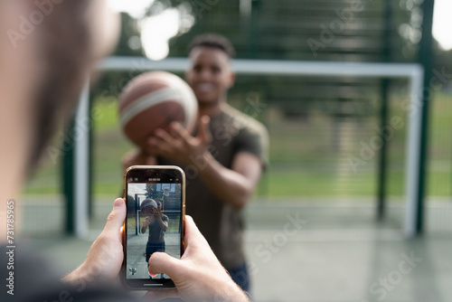 Man photographing friend with basketball ball photo