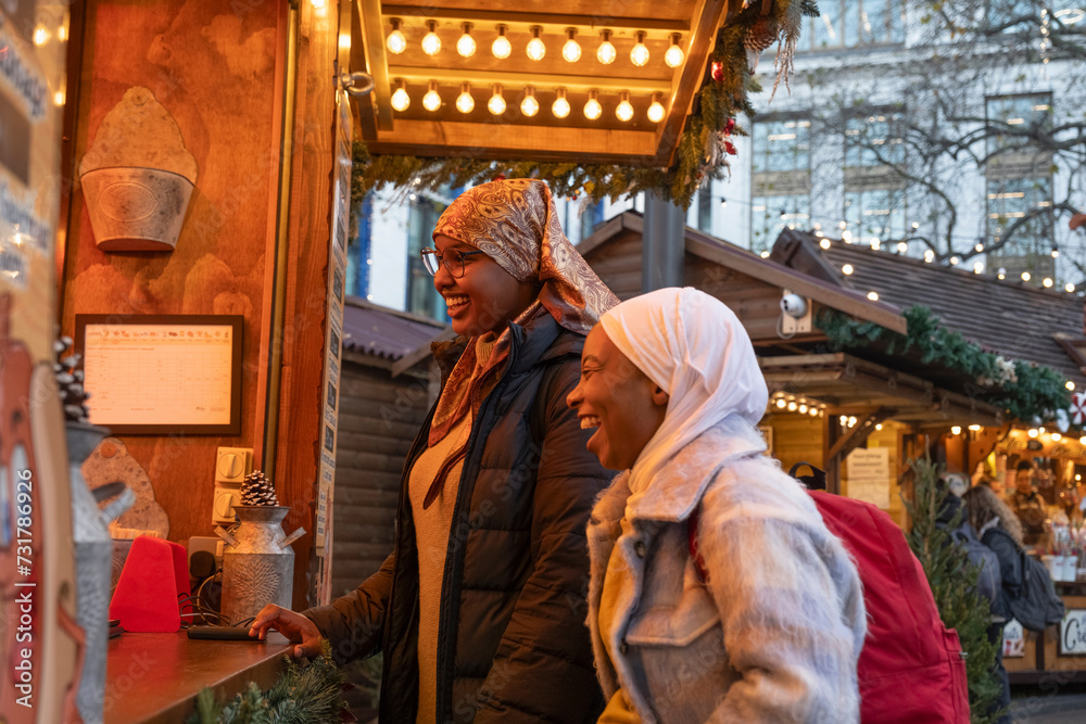 Young female tourists in hijabs visiting Christmas market