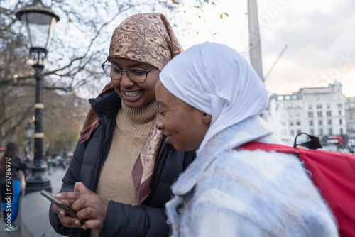 UK, London, Young female tourists in hijabs using phone in Trafalgar Square photo