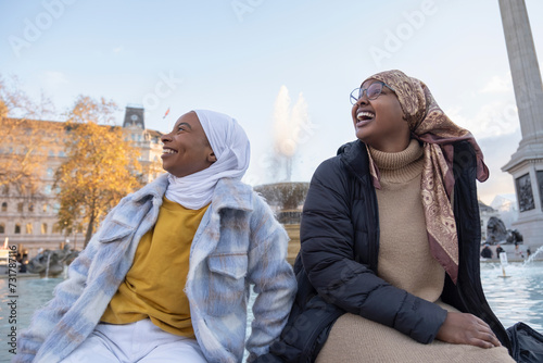 UK, London, Young female tourists in hijabs relaxing in city square