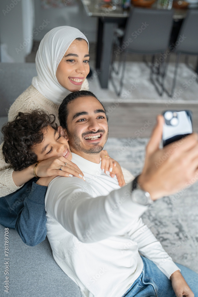Parents and son (6-7) taking selfie on sofa at home Parents and son (6-7) taking selfie on sofa at home