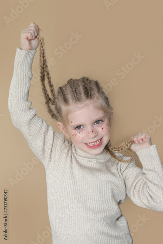 Portrait of cute little blonde girl with boxer braids and glitters om face photo