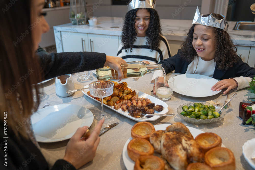 Mother pouring drink to daughters glass at Christmas dinner table