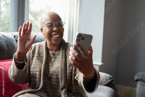 Mature woman sitting in living room with her smart phone