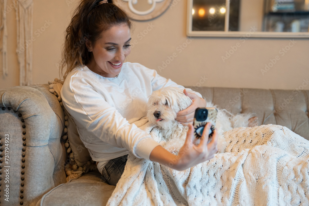 Woman with dog on sofa, using smartphone Woman with dog on sofa, using smartphone
