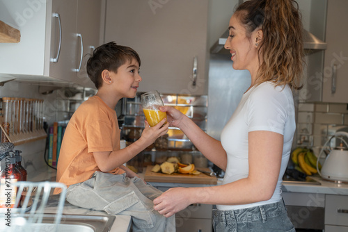 Mother and son (6-7) in kitchen, drinking orange juice
