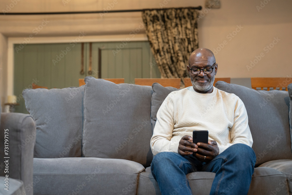 Senior man sitting on sofa and using phone