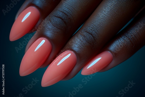 African American womans hand with long nails and peach fuzz color manicure on dark blue background