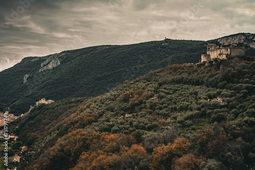 A landscape view, old film style color correction, an old medieval castle on top of the mountain in the middle of forest in Pietra Ligure, Italy