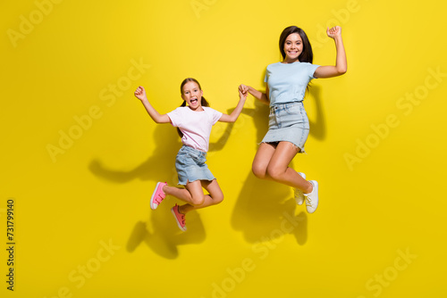 Photo of two girls sisters jumping with raise fists up enjoy kid children sale discounts isolated over bright color background