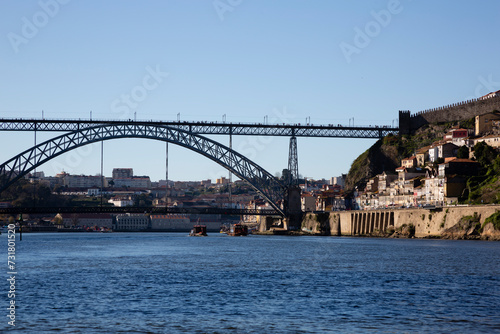 View of the Luis I Bridge, Muralha Fernandina and Gustavo Eiffel Avenue in O Porto on a sunny day with blue sky © casavella