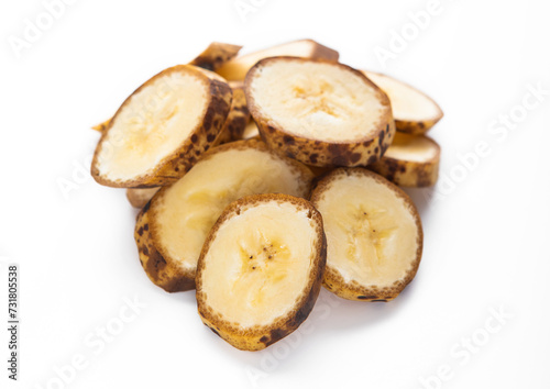 Fresh raw organic banana slices with brown spots on white background.