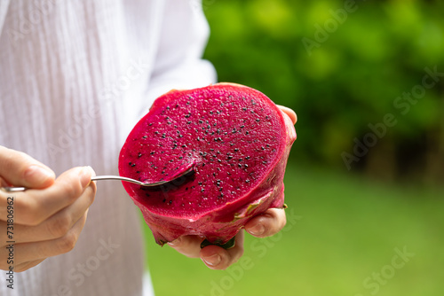 Tableau sur toile girl eats dragon fruit with a spoon, pitahaya, exotic fruit, healthy nutrition,