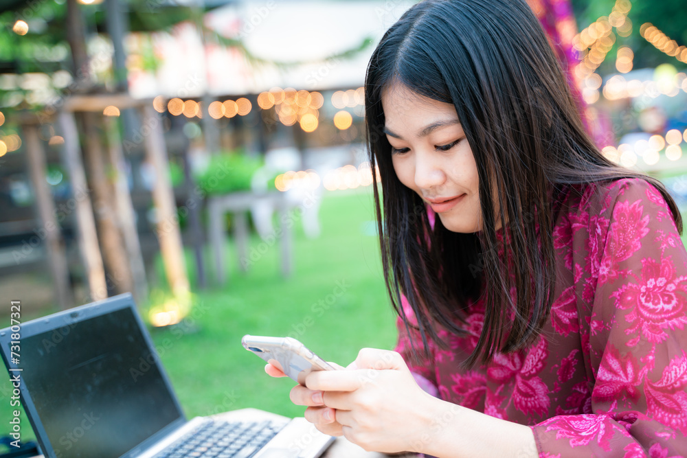 Beautiful asian business women use smartphone text message sitting on grass in party park outdoor background Beautiful asian business women use smartphone text message sitting on grass in party park outdoor background