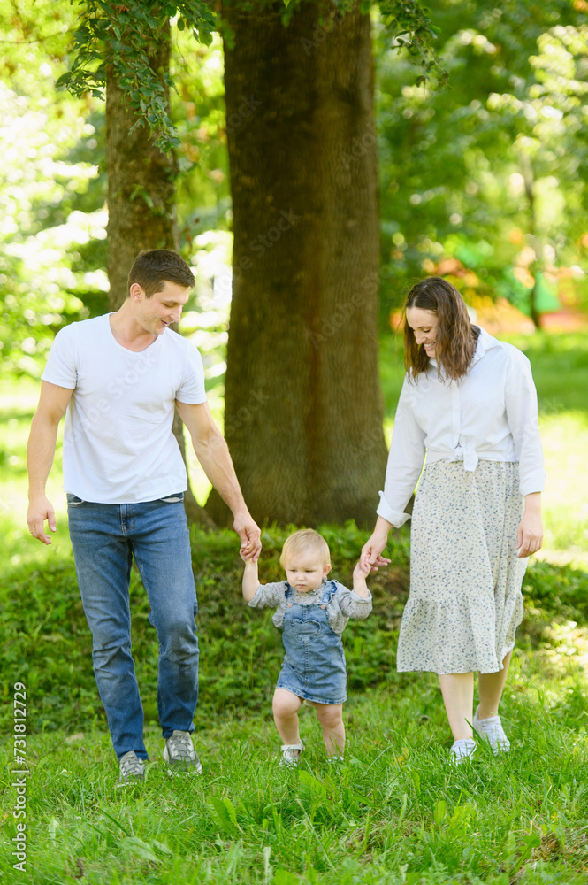 Happy family, dad, mom, child walk together in a park in nature, holding hands. Concept of family vacation, first steps. Happy family, dad, mom, child walk together in a park in nature, holding hands. Concept of family vacation, first steps.