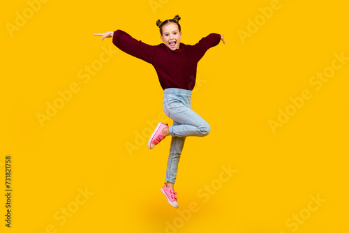 Full size photo of cheerful adorable girl jumping have good mood isolated on yellow color background