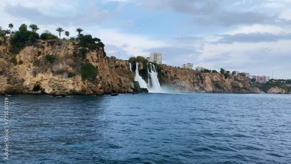 Majestic waterfall cascading from a rocky cliff into the sea in cloudy weather Majestic waterfall cascading from a rocky cliff into the sea in cloudy weather