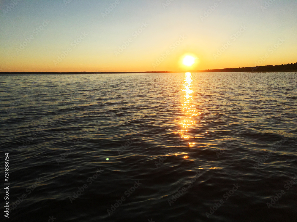 Evening lake with waves against sunset background