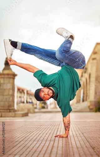 latin American breakdancer guy performing inverted freeze technique on the street