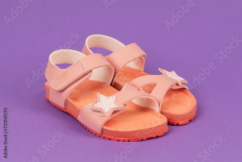 Two pink sandals on purple background. Cute pink sandals for little girl.