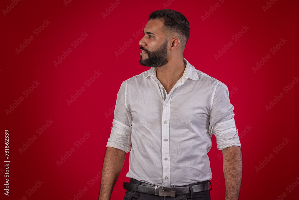 Man, with a beard, in a white shirt, with various facial expressions, on a red studio background Man, with a beard, in a white shirt, with various facial expressions, on a red studio background