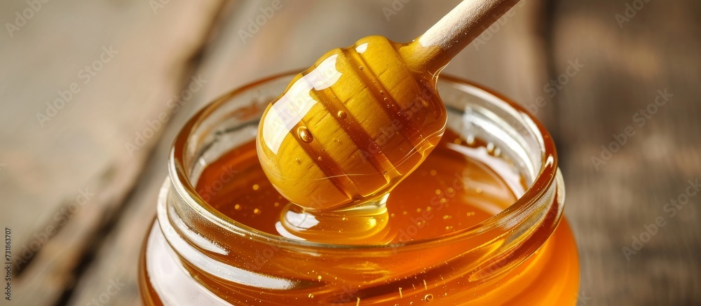 A glass bottle filled with amber liquid, containing a honey dipper sticking out. This drinkware holds a sweet and sticky honey, perfect as an ingredient or a solution in various recipes. A glass bottle filled with amber liquid, containing a honey dipper sticking out. This drinkware holds a sweet and sticky honey, perfect as an ingredient or a solution in various recipes.