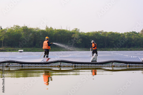 Professional workers cleaning and inspecting solar panels on a floating buoy. Power plant with water, renewable energy sources, Eco technology for industrial electrical energy.