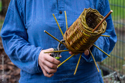 Craftswoman making woven bird house, weaving wicker basket from willow branches photo